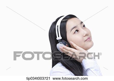 Stock Image - a female student listening on a headphone. Fotosearch