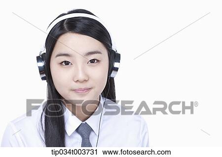 Stock Image - a female student listening on a headphone. Fotosearch