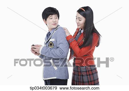 Stock Photo - a female student looking at male student's smartphone over his shoulders. Fotosearch