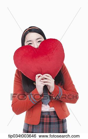 Stock Photograph - a female student posing with a red heart cushion. Fotosearch