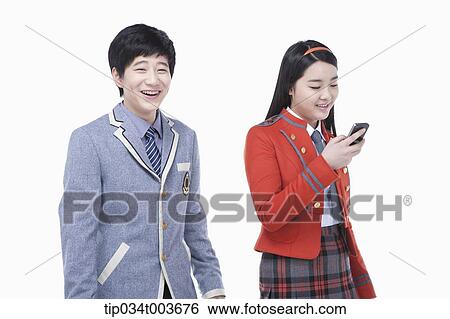 Stock Photograph - a female student reading male student's smartphone screen. Fotosearch
