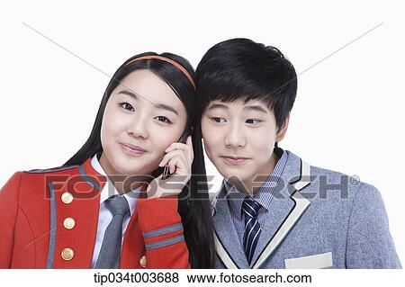 Stock Photo - a female student talking on a mobile phone while male student tries to overhear. Fotosearch