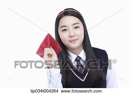 Picture - a female student wearing school uniform ready to throw a paper airplane . Fotosearch