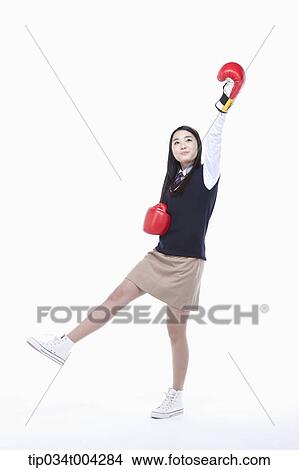 Picture - a female student wearing school uniform punching with boxing gloves . Fotosearch