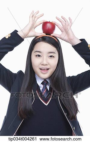 a female student wearing school uniform balancing an apple on her head View Large Photo Image Stock Image - a female student wearing school uniform balancing an apple on her head. Fotosearch