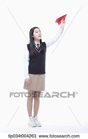 Stock Image - a female student wearing school uniform trying to throw a paper airplane . Fotosearch