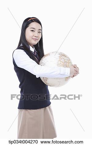 Stock Image - a female student wearing school uniform holding a globe in her arms . Fotosearch
