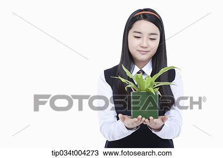 Stock Image - a female student wearing school uniform holding a plant pot. Fotosearch