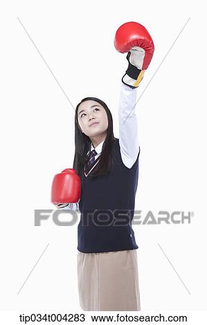 Stock Image - a female student wearing school uniform punching with boxing gloves . Fotosearch