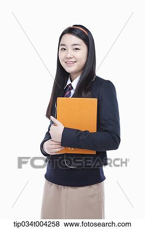 Stock Photo - a female student wearing school uniform holding a book in her arms . Fotosearch