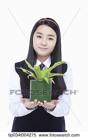 Stock Photography - a female student wearing school uniform holding a plant pot. Fotosearch