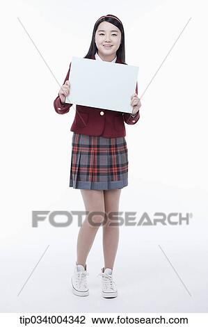 Stock Image - a female student with school uniform holding an empty white paper . Fotosearch
