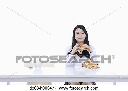 Stock Photo - a female student with school uniform holding a burger. Fotosearch