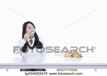 a female student with school uniform eating rice while looking at burgers View Large Photo Image Stock Photo - a female student with school uniform eating rice while looking at burgers. Fotosearch