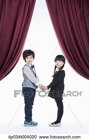 a girl and a boy facing each other hands in hands while looking at audience View Large Photo Image Stock Image - a girl and a boy facing each other hands in hands while looking at audience. Fotosearch