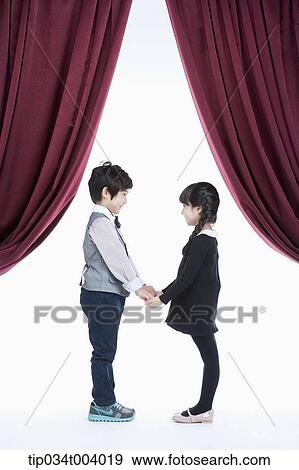 Stock Photo - a girl and a boy facing each other hands in hands on a stage . Fotosearch