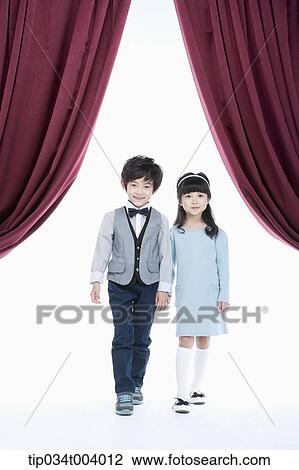 a girl and a boy hand in hand standing on a stage with red curtains View Large Photo Image Stock Image - a girl and a boy hand in hand standing on a stage with red curtains . Fotosearch