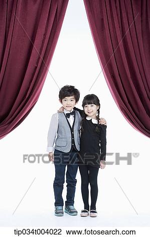 Stock Image - a girl and a boy standing on stage with arms around each other . Fotosearch