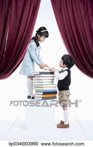 Stock Image - a girl granting a book to a boy under a stage. Fotosearch