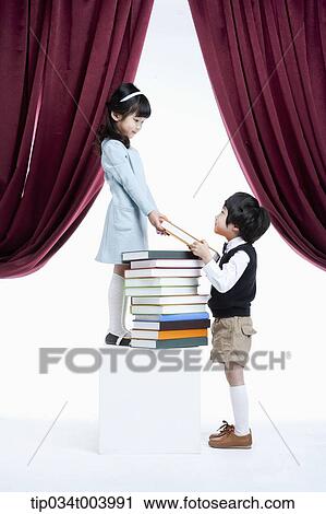 Stock Image - a girl granting a book to a boy under a stage. Fotosearch