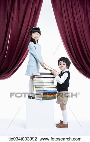 Stock Image - a girl granting a book to a boy under a stage. Fotosearch