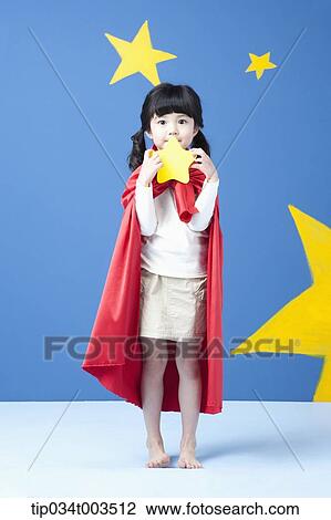 Stock Image - a girl holding a star while wearing a red cape in blue background with stars. Fotosearch