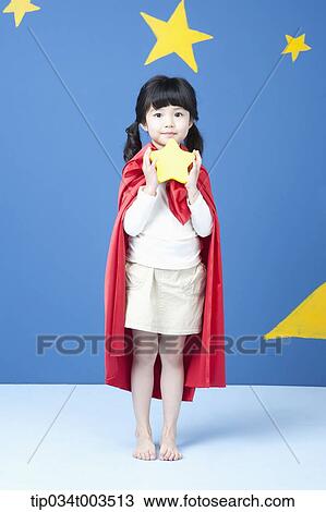 Stock Image - a girl holding a star while wearing a red cape in blue background with stars. Fotosearch