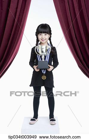 Stock Photo - a girl holding trophy cup with two hands . Fotosearch