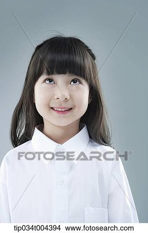 Picture - a girl in white shirt smiling while looking up. Fotosearch