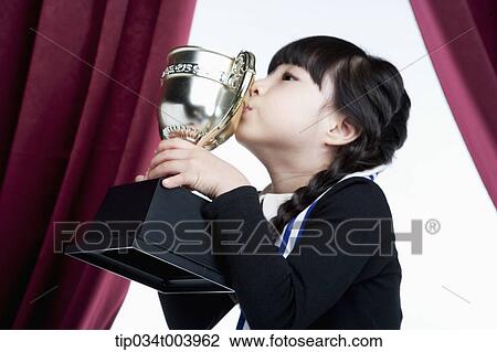 a girl kissing her trophy cup in front of red curtains View Large Photo Image Stock Image - a girl kissing her trophy cup in front of red curtains. Fotosearch