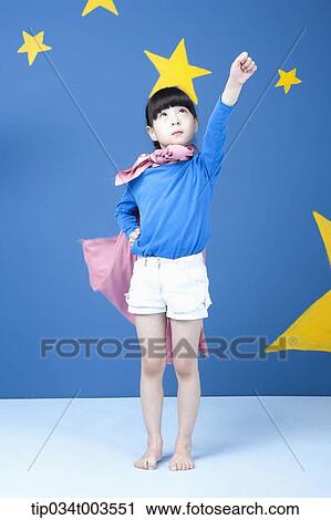 Stock Image - a girl posing like a superwoman with a pink cape around her neck. Fotosearch