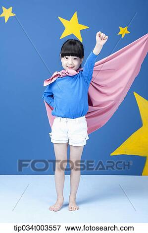 Stock Photo - a girl posing like a superwoman with a pink cape around her neck. Fotosearch