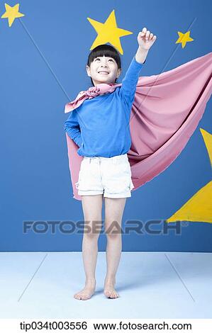 Stock Photograph - a girl posing like a superwoman with a pink cape around her neck. Fotosearch