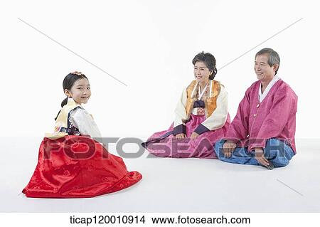 Picture - a girl sitting in front of parents wearing Hanbok. Fotosearch