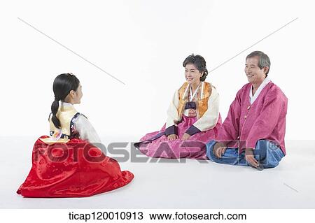 Stock Image - a girl sitting in front of parents wearing Hanbok. Fotosearch