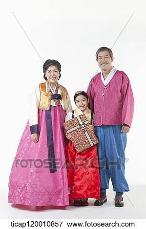 Stock Photo - a girl standing with grandparents wearing Hanbok while holding a present. Fotosearch