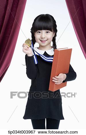 Stock Photo - a girl wearing a medal holding a book in her arm . Fotosearch