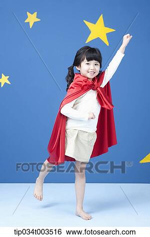 Stock Photograph - a girl wearing a superman cape posing like a superman in blue background with stars. Fotosearch
