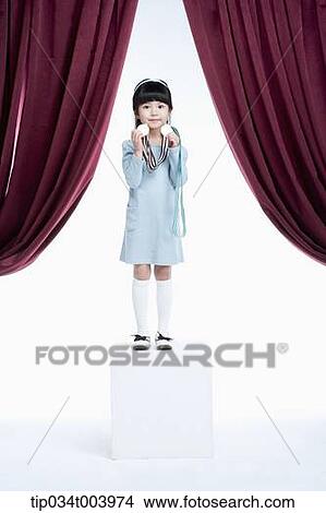 Picture - a girl wearing medals standing on a stage with red curtains. Fotosearch