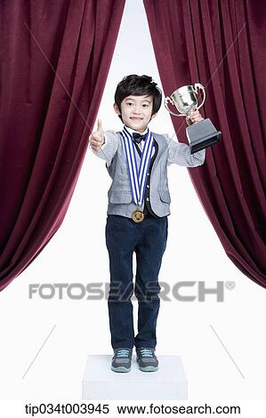 a kid with trophy cup showing his thumbs up on a stage with red curtains View Large Photo Image Stock Photography - a kid with trophy cup showing his thumbs up on a stage with red curtains. Fotosearch