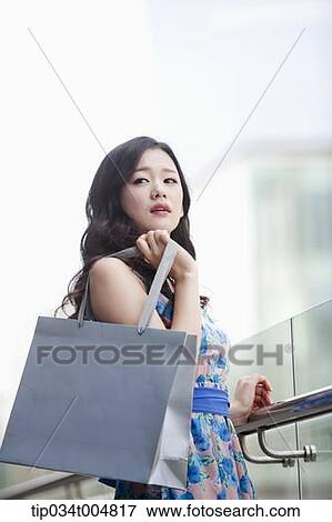 a lady in flower printed dress posing while holding shopping bag View Large Photo Image Stock Photo - a lady in flower printed dress posing while holding shopping bag. Fotosearch