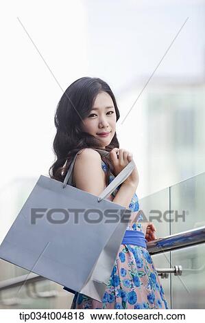 a lady in flower printed dress posing while holding shopping bag View Large Photo Image Stock Photo - a lady in flower printed dress posing while holding shopping bag. Fotosearch