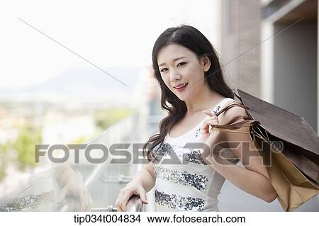Picture - a lady in silver-white striped sleeveless shirt posing with shopping bags . Fotosearch