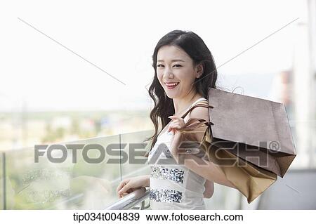 a lady in silver-white striped sleeveless shirt posing with shopping bags View Large Photo Image Stock Photo - a lady in silver-white striped sleeveless shirt posing with shopping bags . Fotosearch