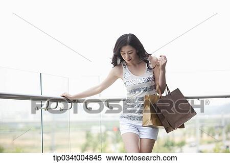 a lady in silver-white striped sleeveless shirt posing with shopping bags View Large Photo Image Stock Photography - a lady in silver-white striped sleeveless shirt posing with shopping bags . Fotosearch