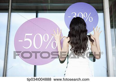 Stock Photo - a lady touching a show window with sale signs. Fotosearch