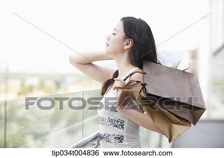 Stock Photograph - a lady with shopping bags posing while eyes closed . Fotosearch