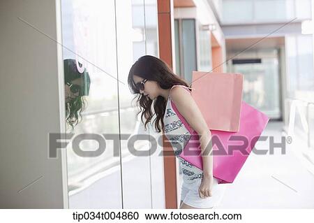 a lady with sunglasses and shopping bags looking on a show window View Large Photo Image Stock Image - a lady with sunglasses and shopping bags looking on a show window. Fotosearch
