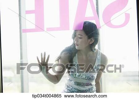 Stock Photography - a lady with sunglasses and shopping bags window shopping during sale. Fotosearch