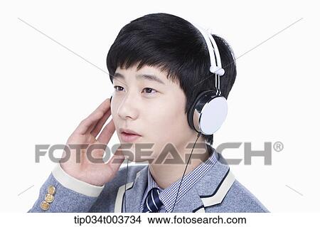 Picture - a male student listening on a headphone. Fotosearch